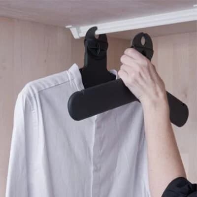 Hånd som henger klær med J-Trac light-henger i garderobe